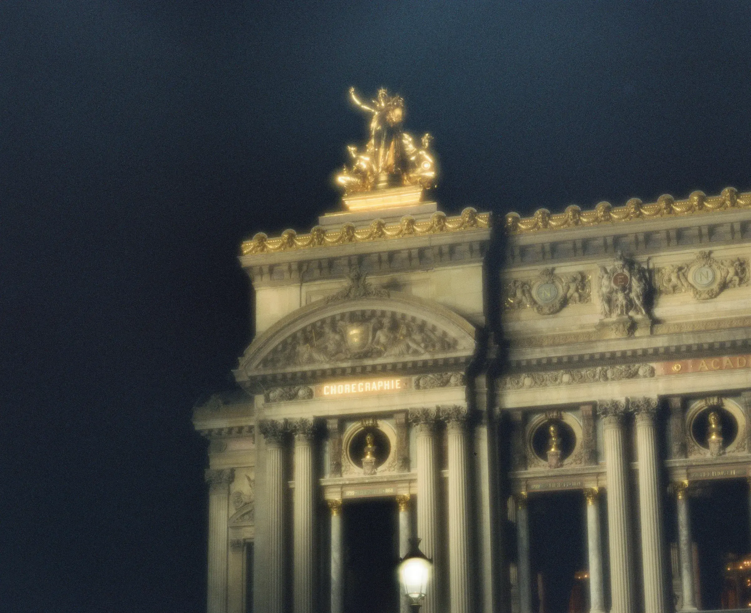 ornate classical facade lit gold at night, arched windows in a row