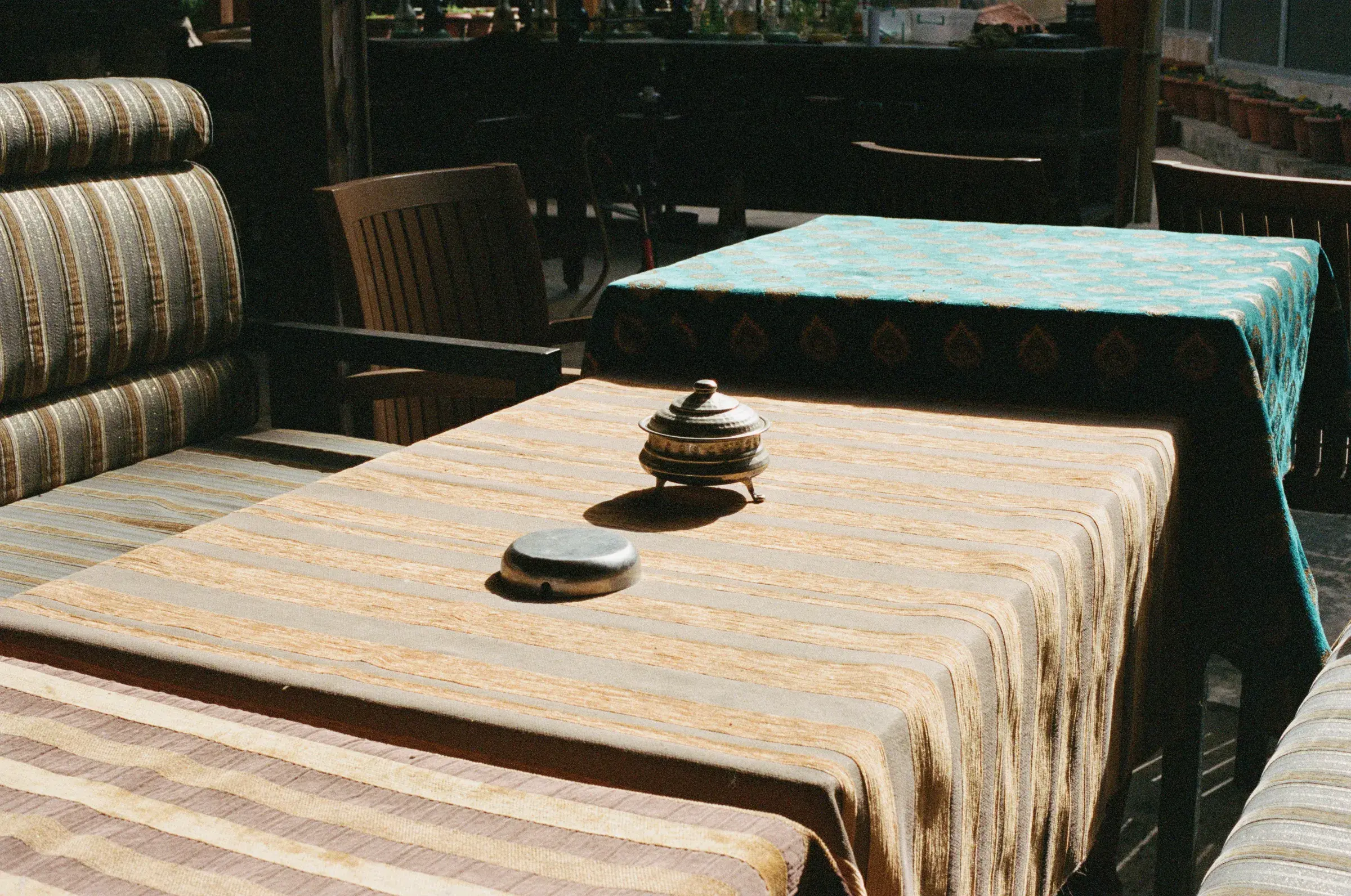 interior with a teal and gold patterned tablecloth, a covered dish, wooden chairs
