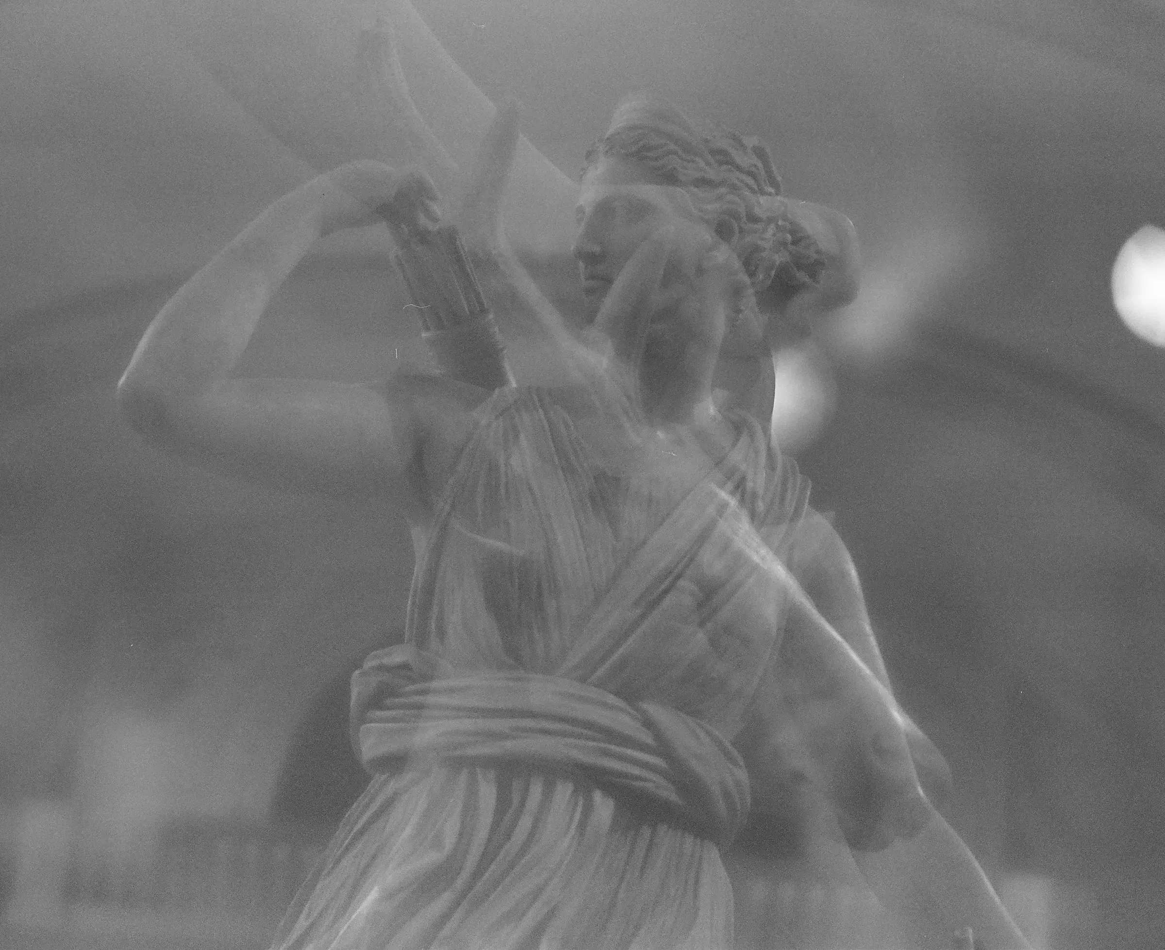 black and white blur of a draped figure caught mid-motion, dreamlike