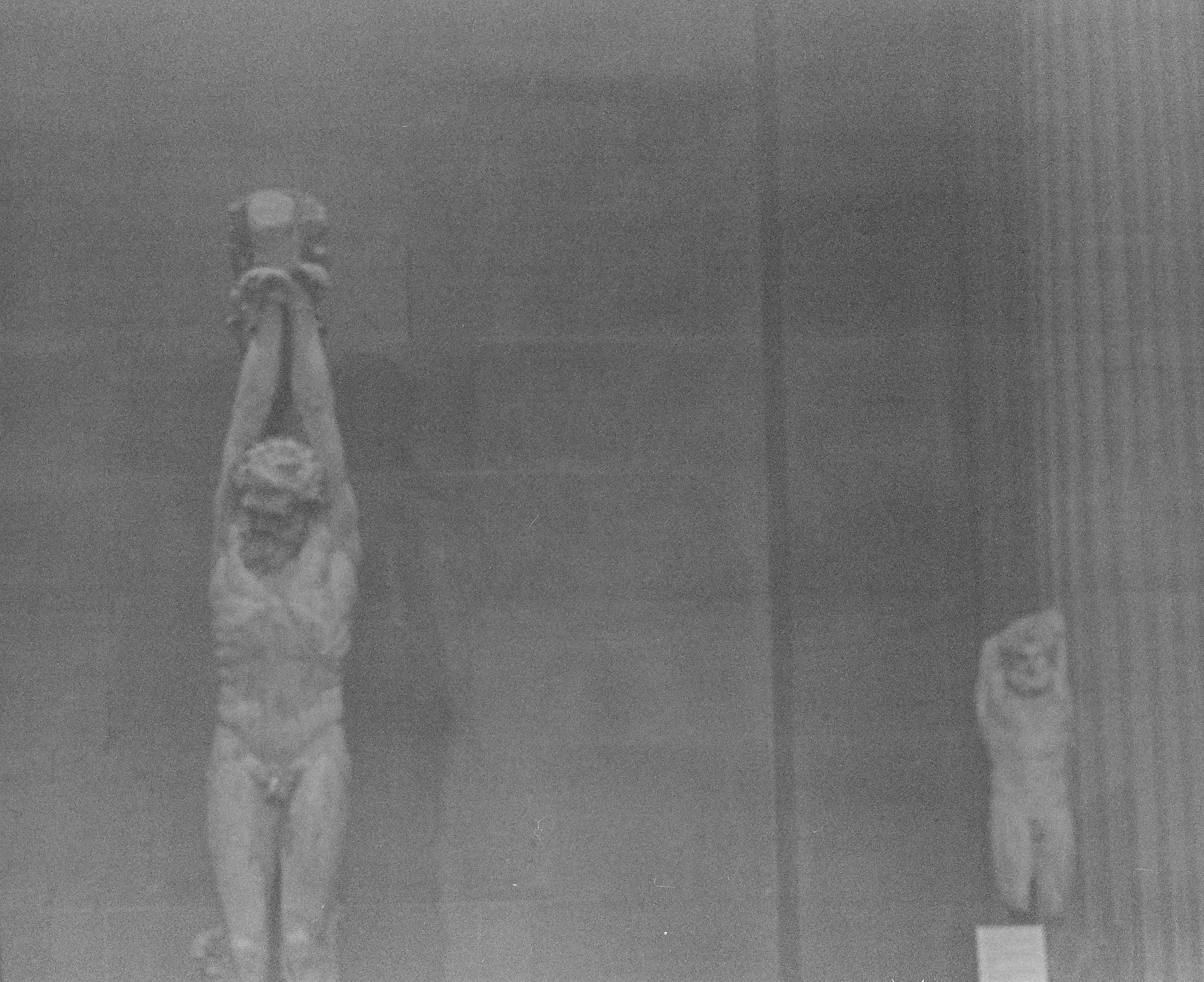grainy black and white classical statue with arms raised overhead