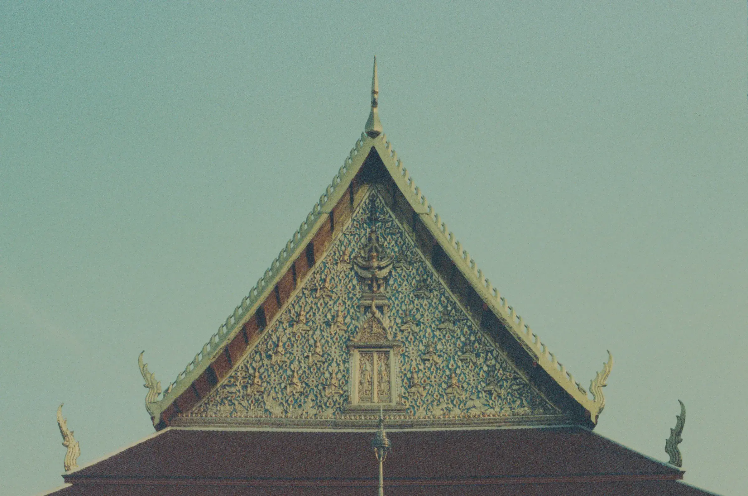Thai temple gable against a pale sky, gold trim along the roofline