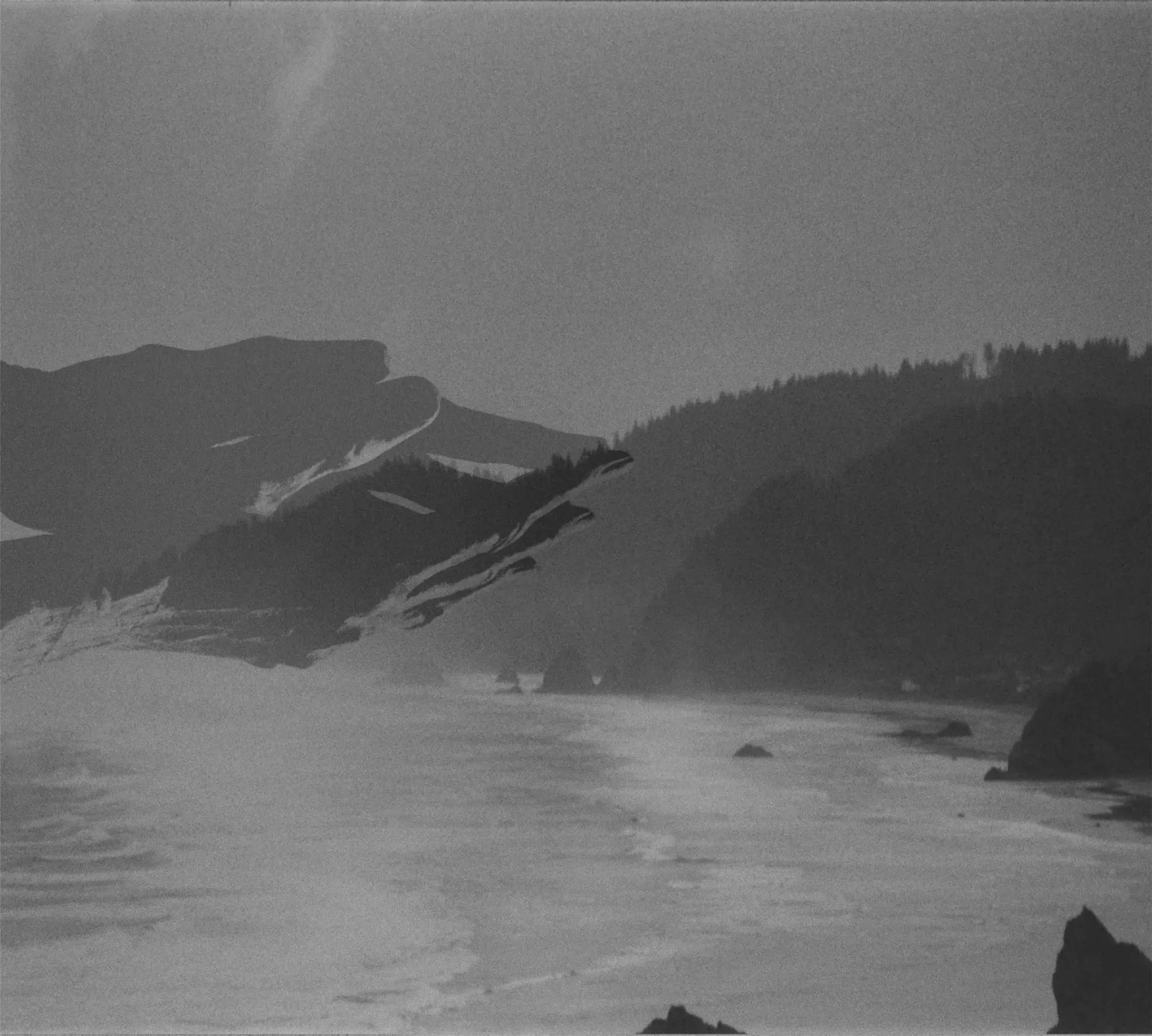 black and white mountain ridge sinking into mist