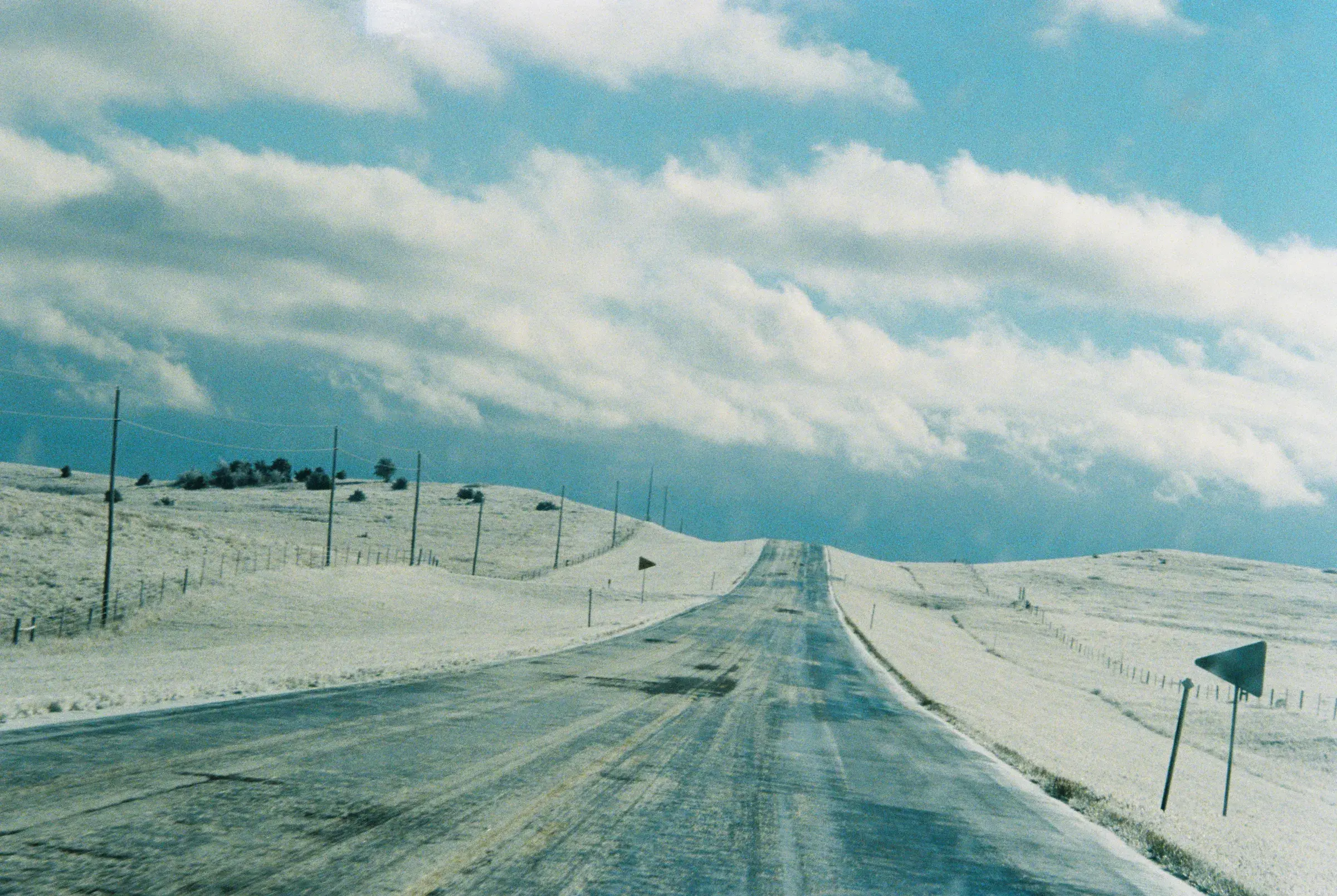 empty road running straight to the horizon under heavy cloud, teal-tinted landscape